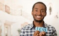 Headshot handsome man holding up small letters spelling the word job and smiling to camera