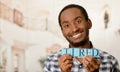 Headshot handsome man holding up small letters spelling the word tired and smiling to camera