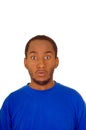 Headshot handsome man wearing strong blue colored t-shirt staring with empty facial expression into camera, white studio