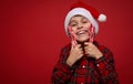 Headshot of handsome tender little boy, adorable smiling child in Santa hat and checkered shirt gently hugs Christmas lollipops