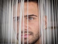 Headshot of handsome young man behind strings curtain Royalty Free Stock Photo