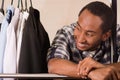 Headshot handsome young man standing inside wardrobe with clothes leaning across metal pole, fashion concept