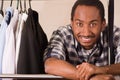 Headshot handsome young man standing inside wardrobe with clothes leaning across metal pole, smiling to camera, fashion Royalty Free Stock Photo