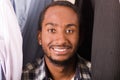 Headshot handsome young man standing inside wardrobe with clothes sorrounding, smiling to camera Royalty Free Stock Photo