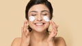 Smiling indian girl apply moisturizing face cream