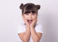 Headshot of impressed attractive little girl opening mouth from amazement and shock holding hands near face