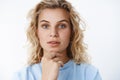 Headshot of interested and focused good-looking creative yong woman with short curly blond hair and blue eyes open lips Royalty Free Stock Photo