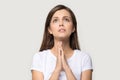 Headshot of millennial woman praying hoping for good looking up