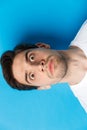 Headshot of pissed-off man losing his temper, looking tensed and angry, standing over blue background