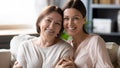 Headshot portrait aged mother and adult daughter embracing posing indoors