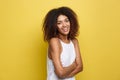 Headshot portrait of beautiful attractive African American woman posting crossed arms with happy smiling. Yellow studio Royalty Free Stock Photo