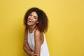 Headshot portrait of beautiful attractive African American woman posting crossed arms with happy smiling. Yellow studio Royalty Free Stock Photo