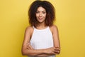 Headshot portrait of beautiful attractive African American woman posting crossed arms with happy smiling. Yellow studio Royalty Free Stock Photo