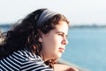 Headshot portrait of beautiful girl looking at the sea against sun