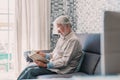 Headshot portrait close up of old happy and relaxed man sitting reading a book at home. Mature male person enjoying free time Royalty Free Stock Photo