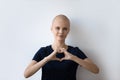 Headshot portrait of hairless sick woman show heart gesture