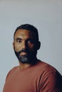 headshot portrait of a handsome thoughtful bearded mid adult man looking at camera against gray background