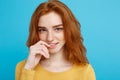 Headshot Portrait of happy ginger red hair girl with freckles smiling looking at camera. Pastel blue background. Copy Royalty Free Stock Photo