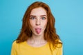 Headshot Portrait of happy ginger red hair girl with funny face looking at camera. Pastel blue background. Copy Space