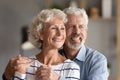 Headshot portrait happy 60s couple hugging standing indoors look away Royalty Free Stock Photo