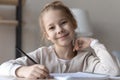 Headshot portrait smiling girl elementary school age pupil at desk Royalty Free Stock Photo