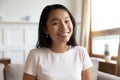 Headshot portrait Vietnamese millennial attractive woman sitting on couch