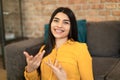 Headshot of positive spanish lady gesturing, chatting remotely, looking at camera in living room interior, closeup