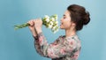 Headshot of pretty young woman with tender smile, healthy skin, carries bouquet of spring flowers, isolated over light blue Royalty Free Stock Photo