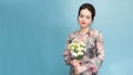 Headshot of pretty young woman with tender smile, healthy skin, carries bouquet of spring flowers,  over light blue Royalty Free Stock Photo