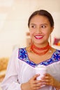 Headshot pretty young woman wearing traditional andean blouse, holding white coffee mug, facing camera, beautiful smile Royalty Free Stock Photo