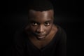 Headshot of serious confident young dark-skinned male standing isolated against black studiobackground.