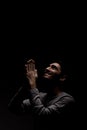 Headshot of serious confident young man praying in dark room. Lit from above and looking up Royalty Free Stock Photo