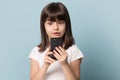 Headshot studio portrait astonished kid girl looking at smartphone screen. Royalty Free Stock Photo