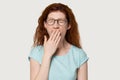 Headshot studio portrait redhead woman yawning cover mouth with hand