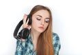 Headshot of a young adorable blonde woman in blue plaid shirt enjoying listening music to big professional dj headphones. Royalty Free Stock Photo