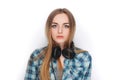 Headshot of a young adorable blonde woman in blue plaid shirt enjoying listening music to big professional dj headphones. Royalty Free Stock Photo