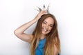 Headshot of young adorable blonde woman with cute smile in hand made princess crown on white background