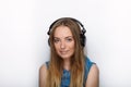 Headshot of young adorable blonde woman with cute smile wearing big black professional monitoring headphones against white studio Royalty Free Stock Photo
