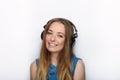 Headshot of young adorable blonde woman with cute smile wearing big black professional monitoring headphones against white studio Royalty Free Stock Photo