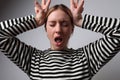 Headshot of young woman creaming and making face grimace indoor. Mindset ideas.