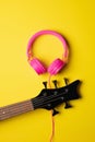 headstock of a five string guitar next to a pair of pink headsets