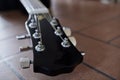 Headstock and tuners of beautiful black acoustic guitar lying on the brick floor closeup. Royalty Free Stock Photo
