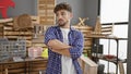 Headstrong young arab carpenter exhibiting his professionalism with a serious face and arms crossed, standing proudly in his