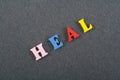 HEAL word on black board background composed from colorful abc alphabet block wooden letters, copy space for ad text. Learning Royalty Free Stock Photo