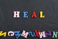 HEAL word on black board background composed from colorful abc alphabet block wooden letters, copy space for ad text. Learning Royalty Free Stock Photo