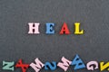 HEAL word on black board background composed from colorful abc alphabet block wooden letters, copy space for ad text. Learning Royalty Free Stock Photo