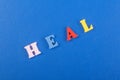 HEAL word on blue background composed from colorful abc alphabet block wooden letters, copy space for ad text. Learning english