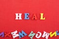 HEAL word on red background composed from colorful abc alphabet block wooden letters, copy space for ad text. Learning english