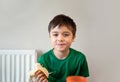 Healthy young boy eating banana, Happy kid having breakfast, Cute Child looking at camera with smiling face.