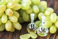 Healing grapes seeds oil in a glass jar, fresh grapes on old wooden background, seed extract has antioxidant and nourishing the sk